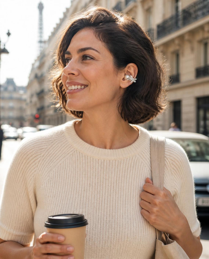Femme qui marche en ville avec un café, un écouteur-bijou à l'oreille